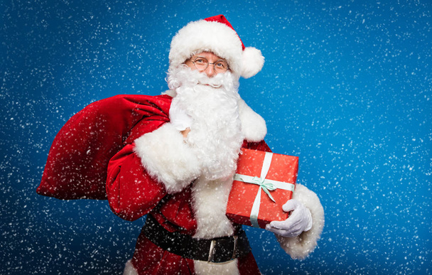  Koncept Vánoc a Nového roku. Portrét muže v kostýmu Santa Clause s dárkem - Fotografie, Obrázek