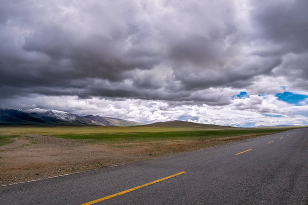 Проезд вперед концептуальный фон - дорога на равнинах в Гималаях с горами и впечатляющими облаками
. - Фото, изображение