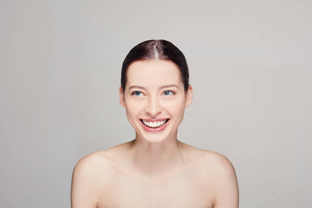 Beautiful girl with natural makeup. Women with clean fresh skin, dark hear and blue eyes. Closeup. Skincare. Nude makeup. Looks at right side and smiles. - 写真・画像