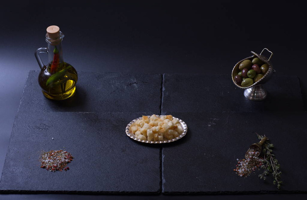 crutones se encuentran junto a una jarra de aceite de oliva y especias sobre un fondo oscuro
 - Foto, Imagen