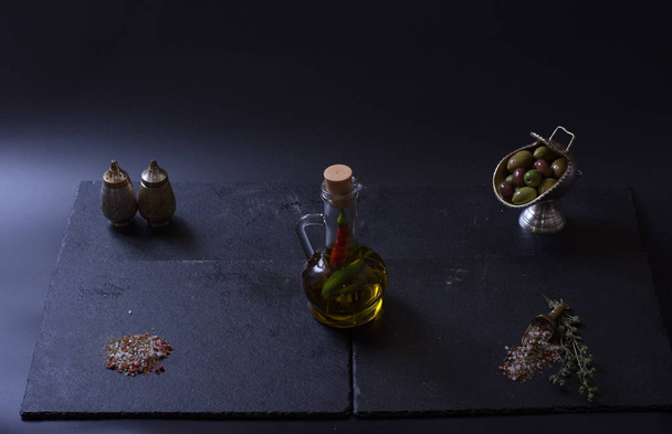 a jug of butter stands next to vegetables and spices on a dark background - Foto, Bild