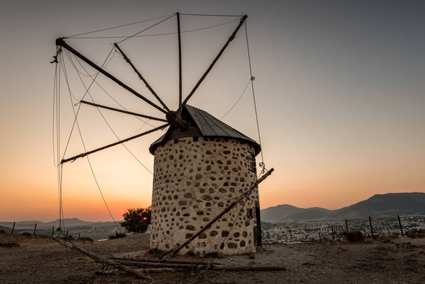 Antigo moinho de vento velho ao pôr do sol na colina na cidade de Bodrum, na Turquia
 - Foto, Imagem