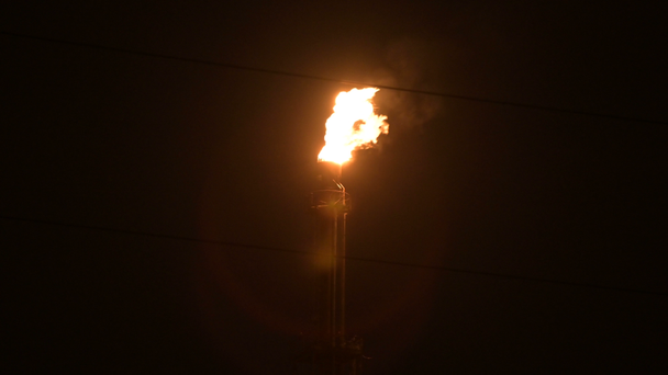 Een nacht schot van een vlamende gasbrander van petrochemische productie in volledige duisternis. Low Key olie verbranding en milieuvervuiling. Ecologie problemen concept - Video