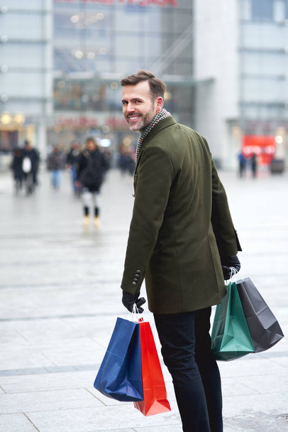Alışveriş çantalı bir adam caddede yürüyor. - Fotoğraf, Görsel