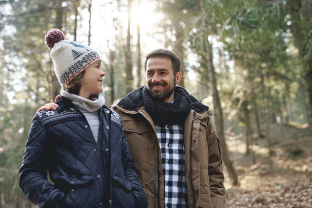 Happy dad and teenage son walking in the autumn forest - Foto, Imagen