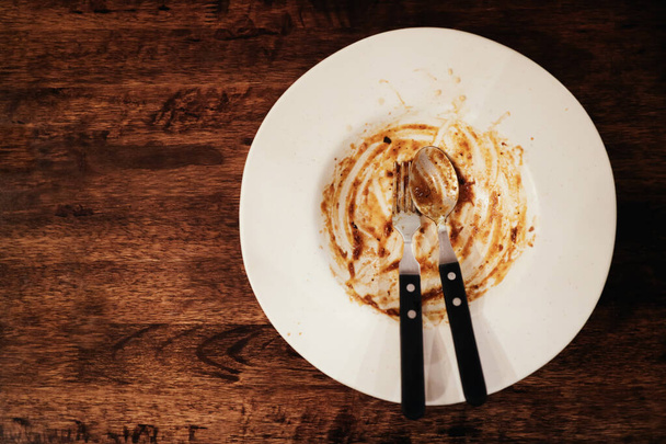 Tenedor y cuchara en la placa vacía blanca después de comer terminado. Parte superior V
 - Foto, Imagen