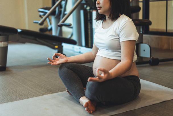 Yoga odasındaki spor salonunda egzersiz yapan aktif hamile bir kadın. Genç, hamile anne.  - Fotoğraf, Görsel