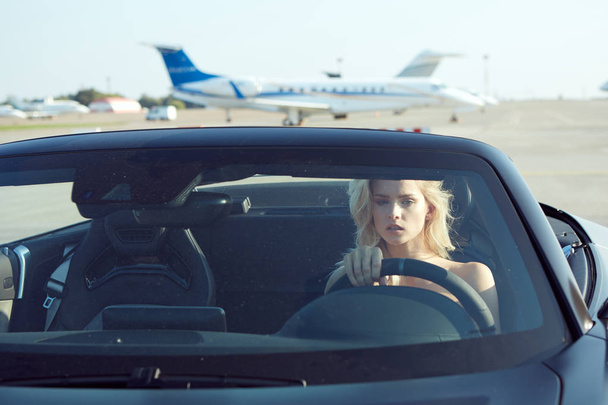 One glamorous blonde woman sit in cabriolet car, glamour girl inside cabrio auto on the runway. No retouch. - Foto, Bild
