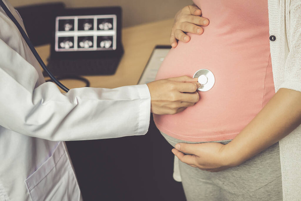 Ευτυχισμένη έγκυος γυναίκα που επισκέπτεται γυναικολόγο γιατρό στο νοσοκομείο ή σε ιατρική κλινική για σύμβουλο εγκυμοσύνης.  - Φωτογραφία, εικόνα