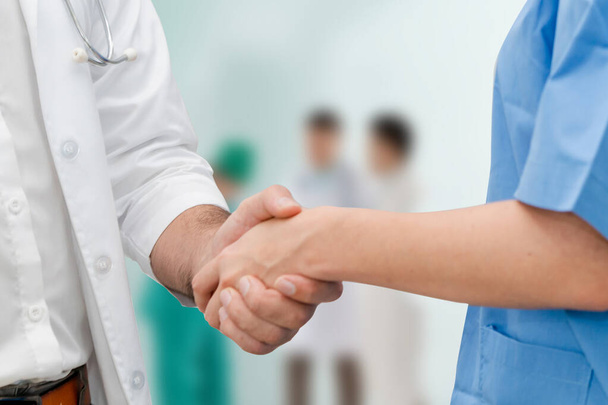 Doctor in hospital handshake with another doctor. Healthcare people teamwork and medical service concept. - Photo, Image
