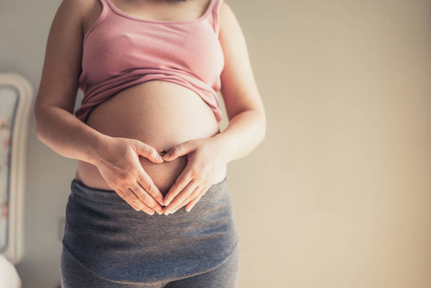 Hamile bir kadın müstakbel çocuğuna bakarken kendini mutlu hissediyor. Doğum öncesi bakım ve kadın hamileliği konsepti. - Fotoğraf, Görsel
