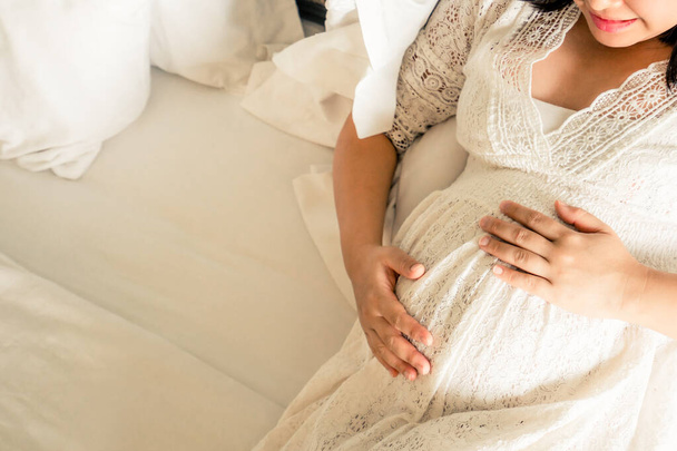 A várandós nő otthon érzi magát, miközben a leendő gyermekéről gondoskodik. Terhesség Terhesség és terhesség fogalma. - Fotó, kép