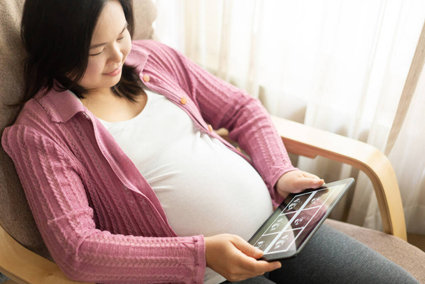 妊娠中の女性は将来の子供の世話をしながら家で幸せを感じています。産前産後ケアと女性妊娠の概念. - 写真・画像