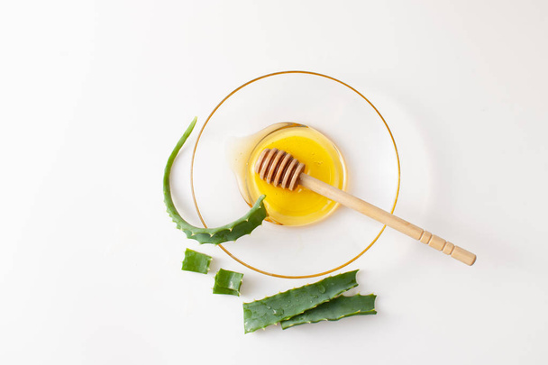 Aloe Vera leaves and fresh honey in bowl on white background - Photo, Image