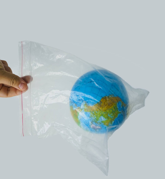Close up male  hand hold in plastic bag Earth world globe isolated on white background. - Valokuva, kuva