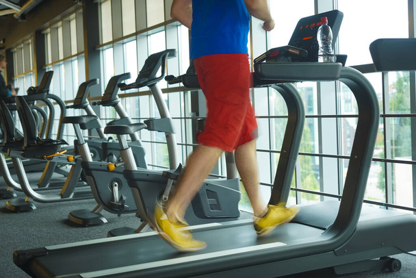Feet with sneakers of male runner. jogger running on treadmill indoors in action - with motion blur. - Fotó, kép