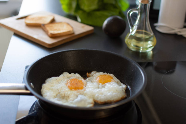 家庭用キッチンのモダンな誘導ストーブで早朝の卵の朝食を準備. - 写真・画像