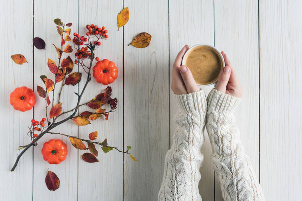 Woman with cup of coffee, leaves, small pumpkins and rowan on white retro wood boards. background. Autumn, fall concept. Flat lay, top view. - Fotoğraf, Görsel