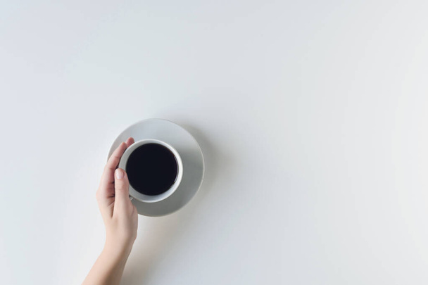 lány kezek tartó csésze fekete kávé a fehér asztalon. Lapos fekvésű, felülnézetű. kávé művészet - Fotó, kép