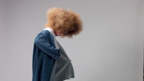 Mixed race black woman with big afro hair in studio in denim oversize shirt - Felvétel, videó