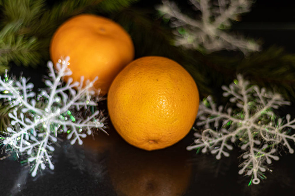 Tangerines on a black background. Christmas tree branch. New Year. Copy space. Vegetarianism - Photo, Image