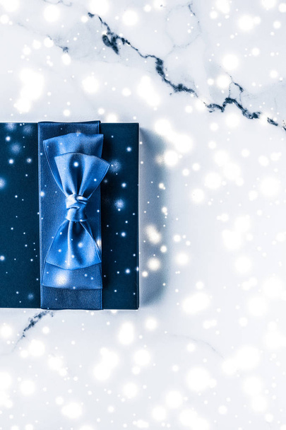 Wintervakantie geschenkdoos met blauwe zijden strik, sneeuwglitter op maart - Foto, afbeelding