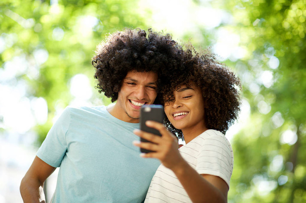 Portrait of happy afro guy taking selfie with smiling young african american woman  - 写真・画像