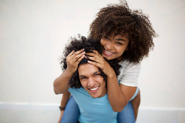 Портрет улыбается африканская девушка американка на спине и держит волосы счастливого афро-человека на белом фоне
 - Фото, изображение
