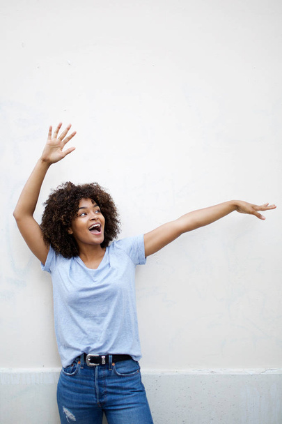 Portrait of cheerful young african american woman laughing with arms raised - Фото, изображение