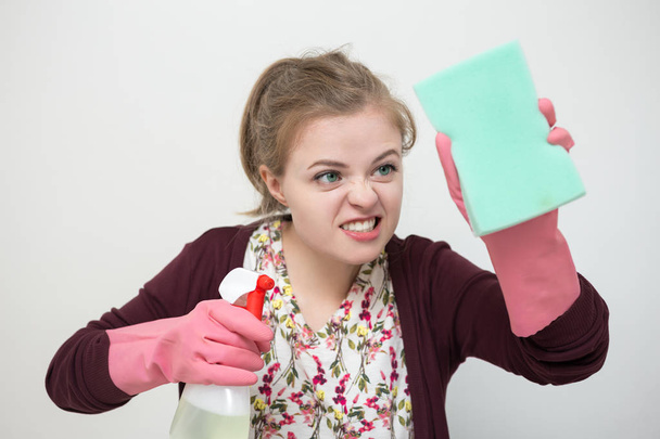 Jovem mulher branca com luvas de borracha, esponja e pulverizador, limpando a casa
 - Foto, Imagem