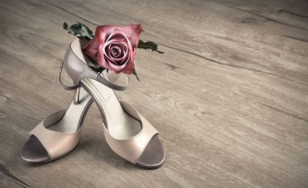 Argentine tango shoes and a rose on a wooden floor, space - Photo, Image