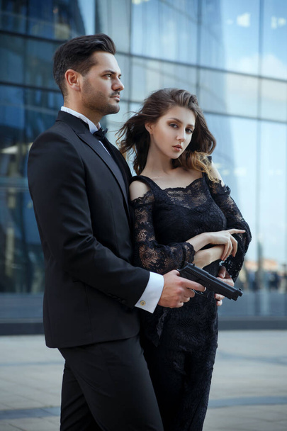 An elegant man with pistols in his hands protects a beautiful girl. - Фото, зображення