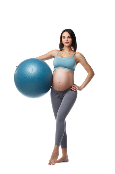 Slim pregnant woman is engaged in fitness with a ball isolated on white background. - Photo, Image