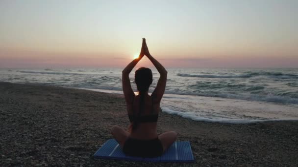 mooie jonge vrouw doen zitten yoga op het strand terwijl kijken naar de zonsondergang. - Video