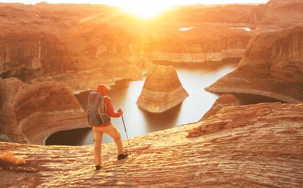 Ongebruikelijke natuurlijke achtergrond. Reflection Canyon on Lake Powell, Utah, Verenigde Staten. Inspirerende wandelende scene-man rustend op het prachtige zonsondergang punt. - Foto, afbeelding