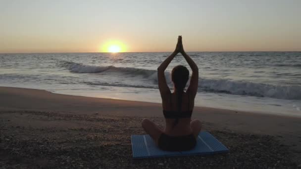 Gyönyörű fiatal nő ül jóga a strandon, miközben nézi a naplementét. - Felvétel, videó