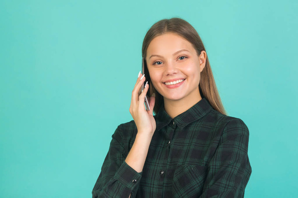 beautiful young woman in a green shirt on a green background with a phone in her hand - Foto, Imagem