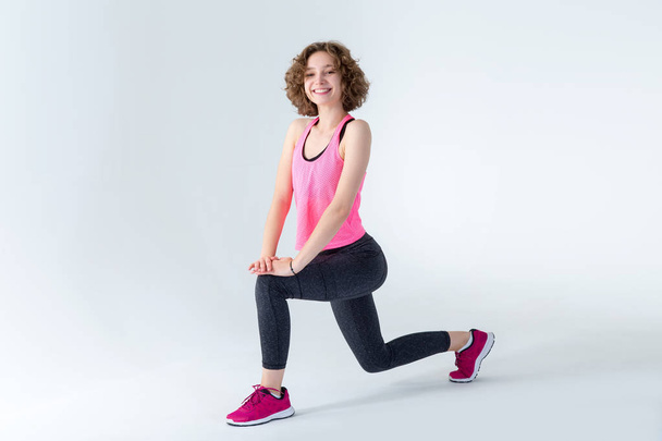 Young fitness woman doing stretching standing on gray background. - Φωτογραφία, εικόνα