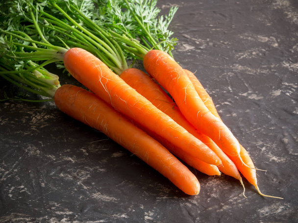 racimo de zanahorias frescas sobre fondo de piedra rústica
.  - Foto, Imagen