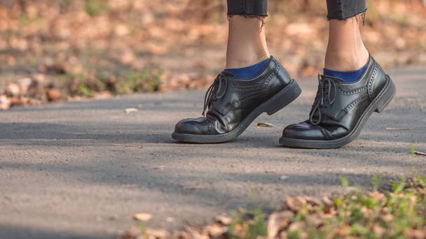  Closeup legs fashionable woman wear black shoes and brown coat. Stylish fall outfit - Φωτογραφία, εικόνα