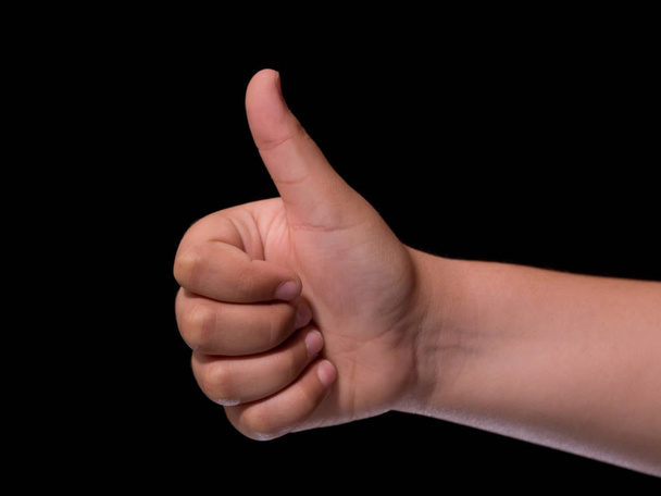 child hand showing ok. Thumbs up. Isolated on black background - Photo, Image
