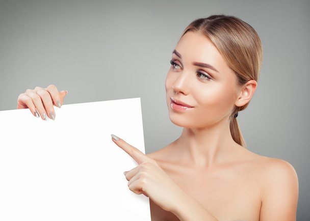 Υγιής γυναίκα μοντέλο που δείχνει και κρατώντας άδειο λευκό κάρτα singboard - Φωτογραφία, εικόνα