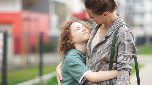 Mother and son hug in the middle of a city street. Happy family, mothers day - Imágenes, Vídeo