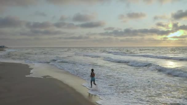 Frau läuft am frühen Morgen allein an der Küste. Sonnenaufgang - Filmmaterial, Video