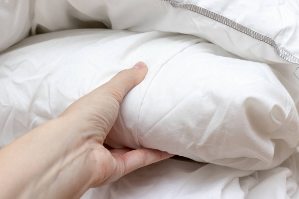 Woman hand taking a blanket from a pile of white bedding items - Foto, imagen