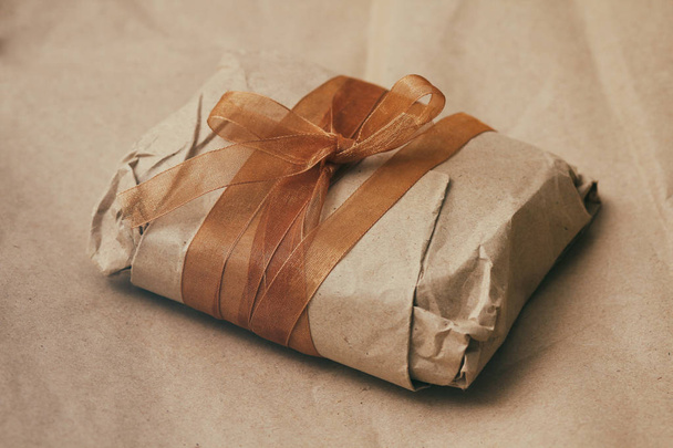 oft pouch wrapped in craft paper and tie brown silk ribbon. Crumpled paper background texture. Delivery service. Online shopping. - Фото, изображение