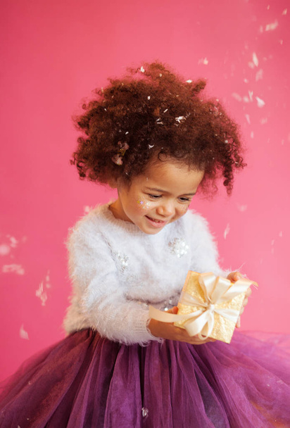 Cute little girl holding a shiny gift box - 写真・画像