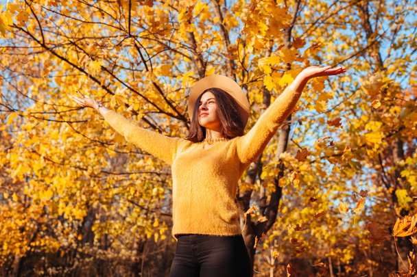 Fall season activities. Woman throwing leaves in autumn forest. Young woman having fun outdoors - Photo, Image