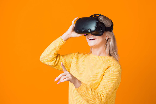 Computer game player uses virtual reality. A young woman in a virtual reality helmet - Foto, immagini