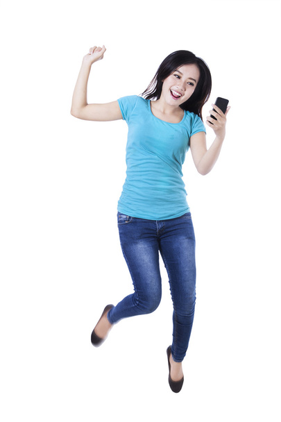 Woman holding cellphone and jumping - Φωτογραφία, εικόνα